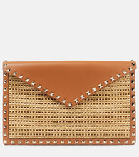 Valentino Garavani Rockstud Large leather-trimmed raffia clutch. Shop Valentino Garavani Clutches for women now.